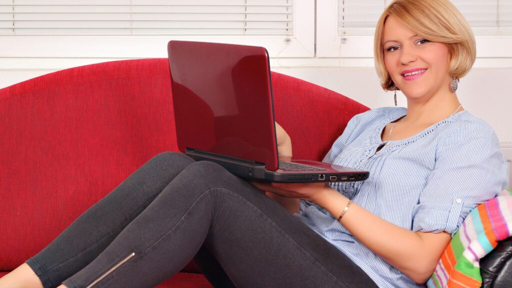 Mujer relajada en sofá con laptop representando emprendimiento desde casa y trabajo digital.